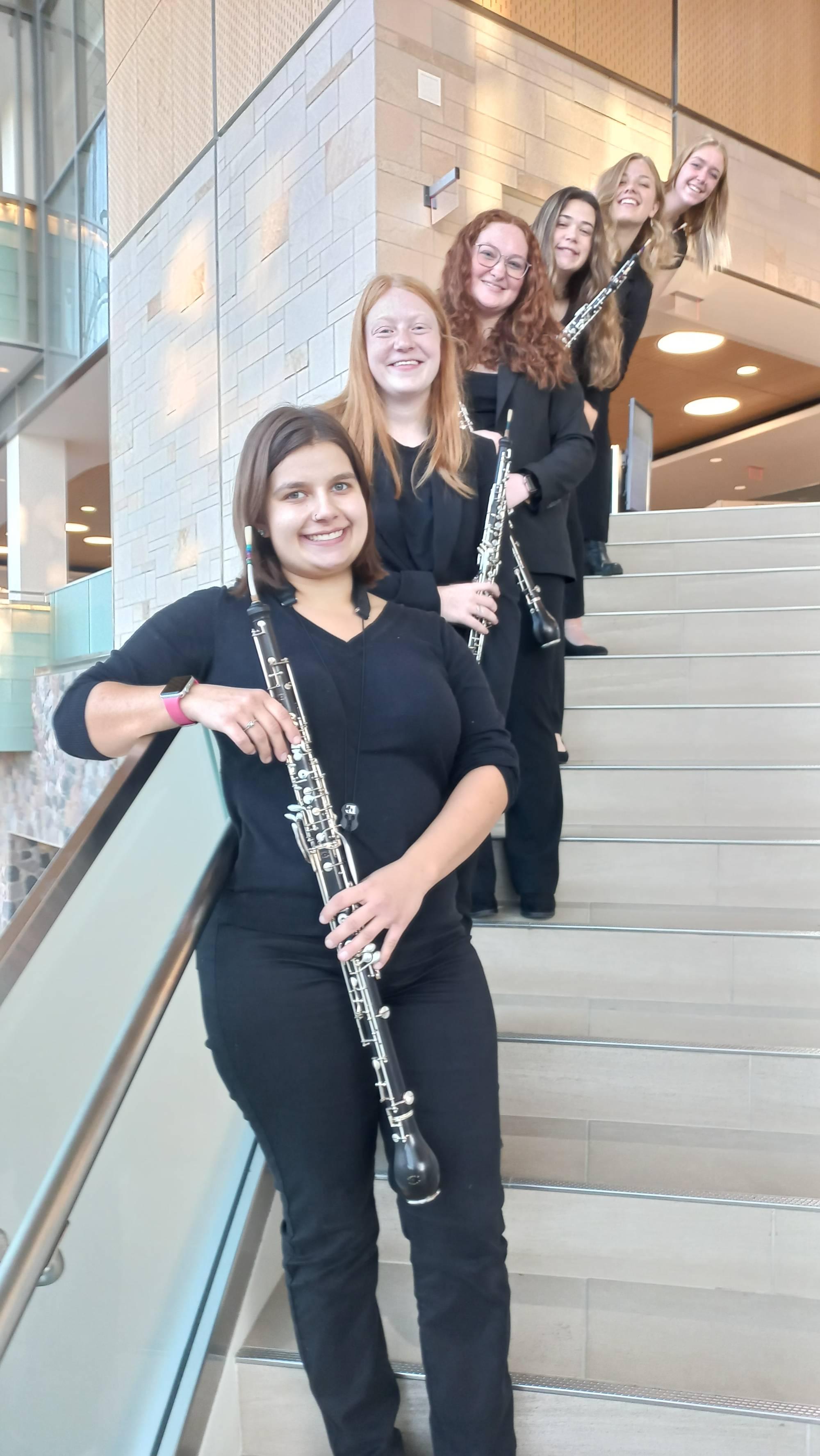 A group of GVSU oboists standing on stairs at the GVSU library.